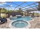 Screened pool area with waterfall feature, fire bowls, hot tub, and covered lounge area at 19313 Pummelo Dr, Orlando, FL 32827