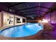 A view of the in-ground pool with a waterfall, and spa with screened enclosure under violet lighting at 19313 Pummelo Dr, Orlando, FL 32827