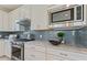 Kitchen showcases stainless steel appliances, granite counters, and a stylish grey subway tile backsplash at 2721 Serenity Meadow Dr, Kissimmee, FL 34744