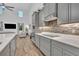 Modern kitchen with gray cabinetry, quartz countertops, and wood flooring adjacent to a living area with a vaulted ceiling at 2940 Scarlett Dr, St Cloud, FL 34772