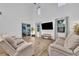 Bright, airy living room featuring vaulted ceilings, a large TV, comfortable seating and natural light streaming in from multiple windows at 2940 Scarlett Dr, St Cloud, FL 34772