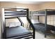 Neutral bedroom featuring bunkbeds with sturdy black metal frames, complemented by soft gray bedding and a window view at 3039 Boating Blvd. Blvd, Kissimmee, FL 34746