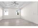 Spacious, bright bedroom featuring neutral walls, tray ceiling, ceiling fan, and wood-look tile flooring at 31905 Larkspur Ave, Eustis, FL 32736