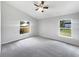 Bright bedroom with plush carpet, ceiling fan, and two large windows overlooking a serene backyard at 332 Lake Doe Blvd, Apopka, FL 32703