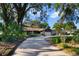 View of a single-story home with stone accents, mature landscaping, and a long driveway at 342 Oak Estates Dr, Orlando, FL 32806