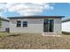 The backyard featuring a sliding glass door and windows under a blue sky at 3876 Giorgio Dr, Winter Haven, FL 33884