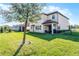 Well-manicured backyard featuring lush green grass, trees, and covered patio, with partial view of home exterior at 612 Via Isabelle Dr, Debary, FL 32713