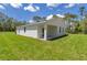 Back exterior view of this bright white home, with ample green grass and a partially-covered patio at 7007 Sw 131St Ave, Ocala, FL 34481