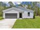 Charming single-story home with a well-manicured lawn and a gray garage door, surrounded by lush trees at 7007 Sw 131St Ave, Ocala, FL 34481