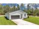 Single-story home with board and batten siding, featuring a gray garage door, and a well-kept green lawn at 7007 Sw 131St Ave, Ocala, FL 34481