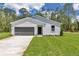 Charming exterior view of home featuring a lush lawn, concrete driveway, and a gray garage door at 7007 Sw 131St Ave, Ocala, FL 34481