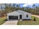 Modern one-story home featuring a gray garage door, a well-maintained lawn, and tasteful landscaping at 7117 Sw 131St Ave, Ocala, FL 34481