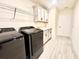 Laundry room with black washer/dryer, storage cabinets, and a utility sink at 760 Annabell Ridge Rd, Minneola, FL 34715
