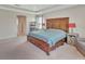Bright main bedroom with a tray ceiling, plush carpet, and a large wooden bed frame at 760 Annabell Ridge Rd, Minneola, FL 34715