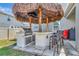 Outdoor kitchen with bar, tiki hut, stainless steel grill and comfortable seating at 760 Annabell Ridge Rd, Minneola, FL 34715
