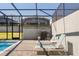 Screened-in pool area featuring two lounge chairs, a grill, and views of the backyard at 926 Paradise Dr, Davenport, FL 33897