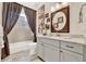 Stylish bathroom featuring a vanity with granite countertop, decorative mirror, and bathtub with shower at 9346 San Jose Blvd, Howey In The Hills, FL 34737