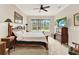 Cozy bedroom with a wooden bed frame, dresser, television, ceiling fan, and a large window at 9346 San Jose Blvd, Howey In The Hills, FL 34737