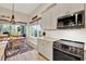 Modern kitchen with stainless steel appliances, tile backsplash, and an adjacent dining area with large windows at 9346 San Jose Blvd, Howey In The Hills, FL 34737