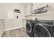 Well-organized laundry room with gray wood floors, modern appliances, and plenty of storage space at 9346 San Jose Blvd, Howey In The Hills, FL 34737
