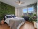 Bedroom featuring hardwood floors, a queen bed, and a lush green wall with plant decor at 1091 Eaglecrest Dr, Winter Garden, FL 34787