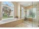 Bright bathroom features a soaking tub next to a large window and a glass enclosed shower at 1232 Scandia Ter, Oviedo, FL 32765