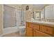 Well-lit bathroom with a shower-tub combo, wooden cabinets, and a framed mirror at 151 Castaway Beach Way, Kissimmee, FL 34746