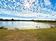 Sunlit view of a lake with interesting cloud formations and a grassy shoreline at 1552 Broken Oak Dr # B, Winter Garden, FL 34787