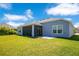 Grassy backyard with a covered patio area attached to the house on a sunny day at 1959 Keel Ct, The Villages, FL 34762
