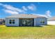 Expansive backyard with lush green grass, a covered patio, and a view of the house exterior at 1959 Keel Ct, The Villages, FL 34762