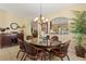 Cozy dining area with a glass table, comfortable chairs, an elegant chandelier, and a large houseplant at 2508 Archfeld Blvd, Kissimmee, FL 34747