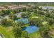 Aerial view of community tennis and basketball courts next to condos, parking, and a pond on a sunny day at 2548 Archfeld Blvd, Kissimmee, FL 34747