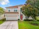 Charming two-story house featuring a red tile roof, two-car garage and mature landscaping at 2548 Archfeld Blvd, Kissimmee, FL 34747
