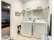 Functional laundry room with washer, dryer, shelving, ironing board, and access to the garage at 2548 Archfeld Blvd, Kissimmee, FL 34747