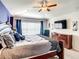 A well-lit main bedroom featuring a ceiling fan, TV, and decorative accent wall at 2548 Archfeld Blvd, Kissimmee, FL 34747