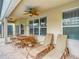 Inviting covered patio with a ceiling fan, dining table, chairs and lounge chairs at 2548 Archfeld Blvd, Kissimmee, FL 34747