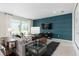This modern living room features a blue accent wall with a large tv and a sliding glass door at 2725 Serenity Garden Dr, Kissimmee, FL 34744