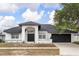 Inviting single-story home with a dark roof, black door, a two-car garage, and manicured landscaping at 2930 Paddington Way, Kissimmee, FL 34747