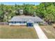 Charming single-story home with a long driveway, blue shutters, and lush landscaping at 295 W Charlotte Ave, Eustis, FL 32726