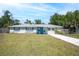 Charming single-story home with a well-maintained lawn, vibrant blue shutters and door, and mature trees at 295 W Charlotte Ave, Eustis, FL 32726