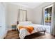 A cozy bedroom featuring a queen bed, neutral curtains, hardwood floors, and a bright window at 301 S Palmetto Ave, Sanford, FL 32771