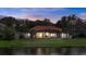 Rear view of a beautiful house overlooking a serene lake with a screened lanai and expansive backyard at 3156 Winding Pine Trl, Longwood, FL 32779