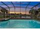 Inviting screened pool area with a spa and picturesque views of the adjacent lake and lush surroundings at sunset at 3156 Winding Pine Trl, Longwood, FL 32779