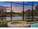 Close-up of a spa adjacent to a screened pool, offering views of the lake and verdant landscaping at sunset at 3156 Winding Pine Trl, Longwood, FL 32779
