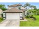 Two-story home featuring an attached two-car garage, mature landscaping, and tropical palm trees at 3408 Idlegrove Ct, Orlando, FL 32822