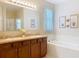 Bathroom featuring double sinks, a soaking tub and a well-lit mirror with decorative sconces at 3620 Chandler Estates Dr, Apopka, FL 32712