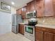 Modern kitchen with stainless steel appliances, tile backsplash, and brown cabinetry at 3620 Chandler Estates Dr, Apopka, FL 32712