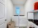 Laundry room with front load washer and dryer and open shelving with ample storage at 3764 Shoveler Ave, Leesburg, FL 34748
