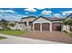 Elegant home featuring a three-car garage, lush landscaping, and a stylish stone entryway at 4419 Liberty Bell Cv, Orlando, FL 32817