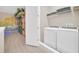 Bright laundry room with a washer, dryer, overhead shelving, and themed wall art in the connecting hallway at 480 Burma St, Kissimmee, FL 34747